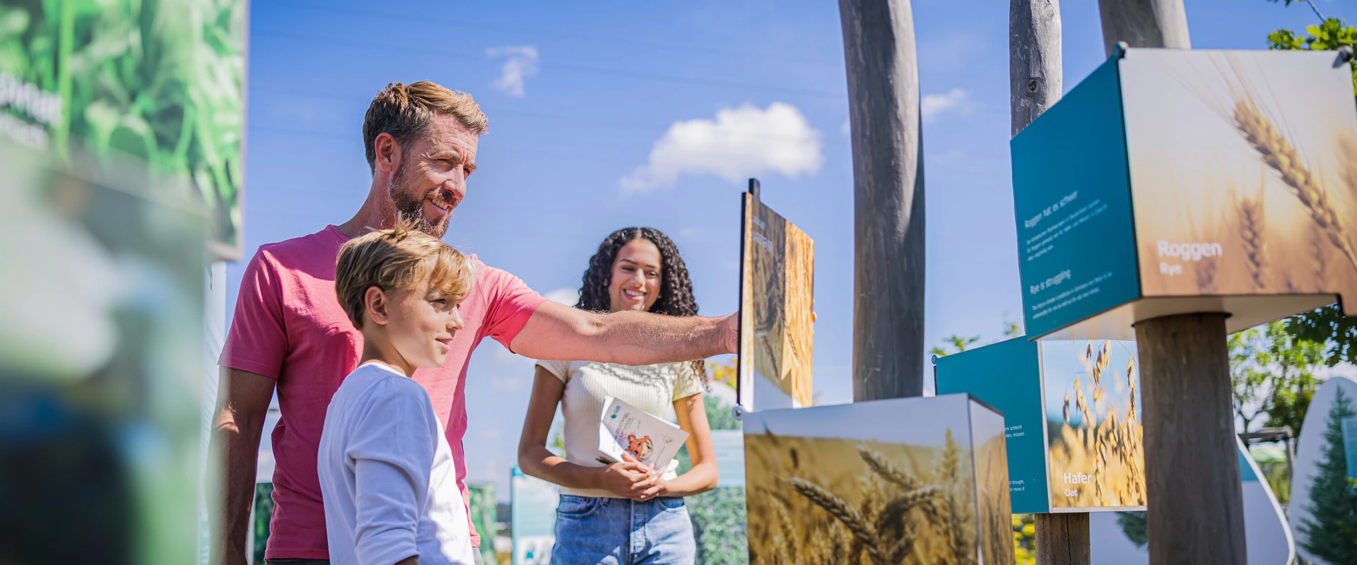Familie betrachtet Infotafeln im Themenpark der KLIMA ARENA.